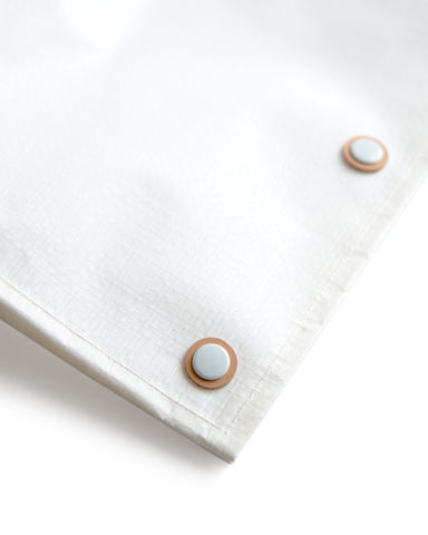 Detail image of the snaps for the hender scheme picnic bag. Each snap is coated in white and is layered on top of a ring of hender scheme signature cow leather.