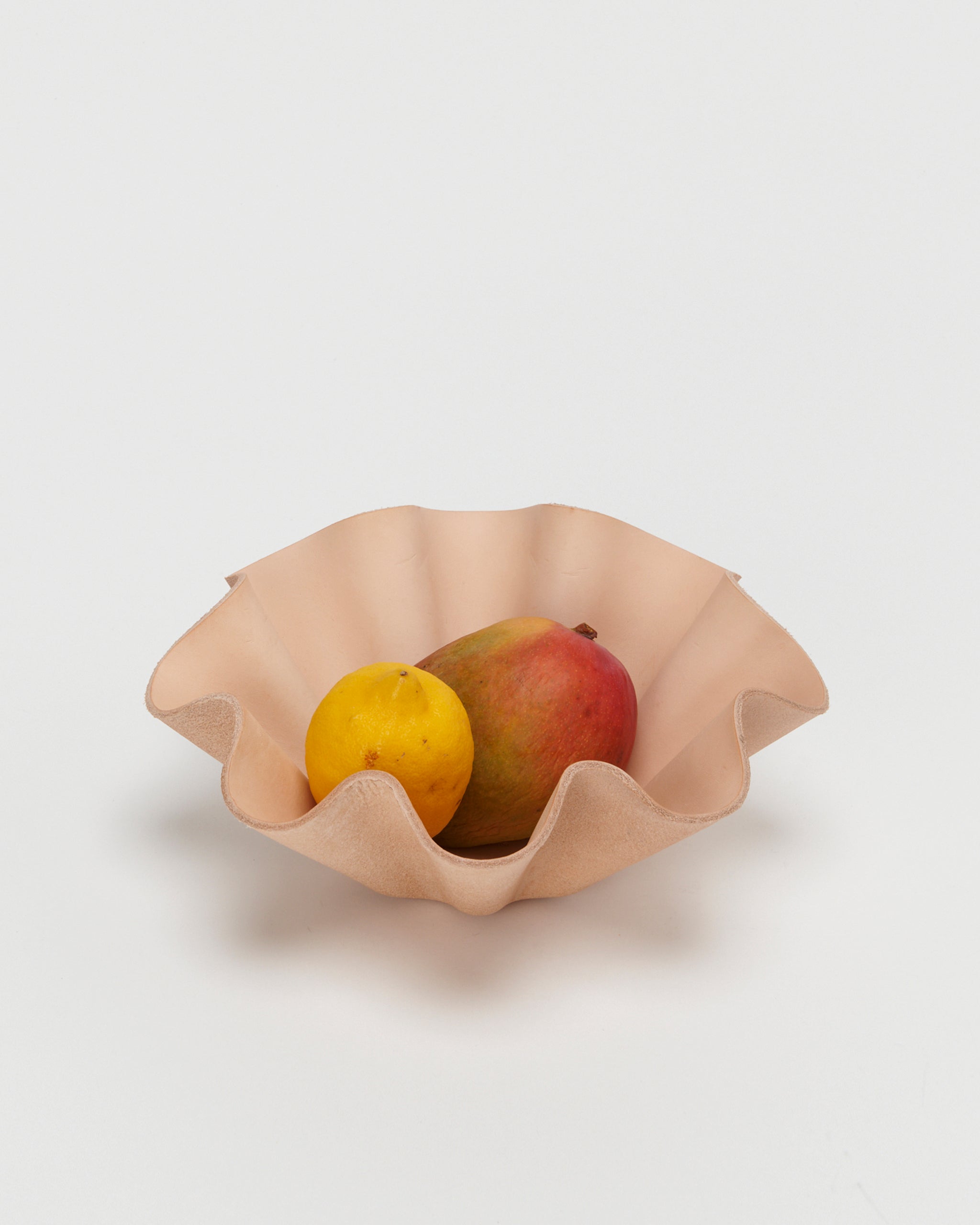 Leather Shell Bowl by Hender Scheme in large with fruits in the bowl on a gray background