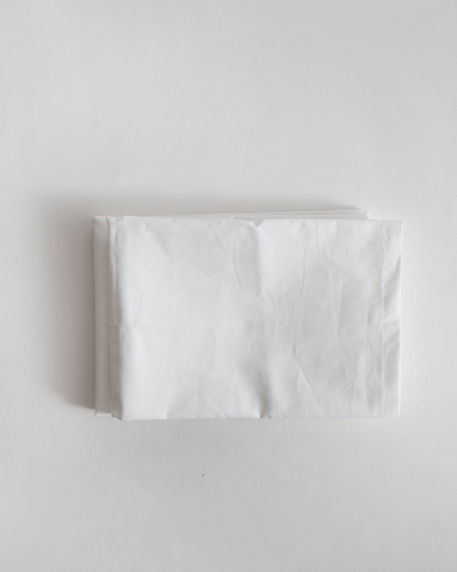 White folded pillowcase by iwata on a light gray background