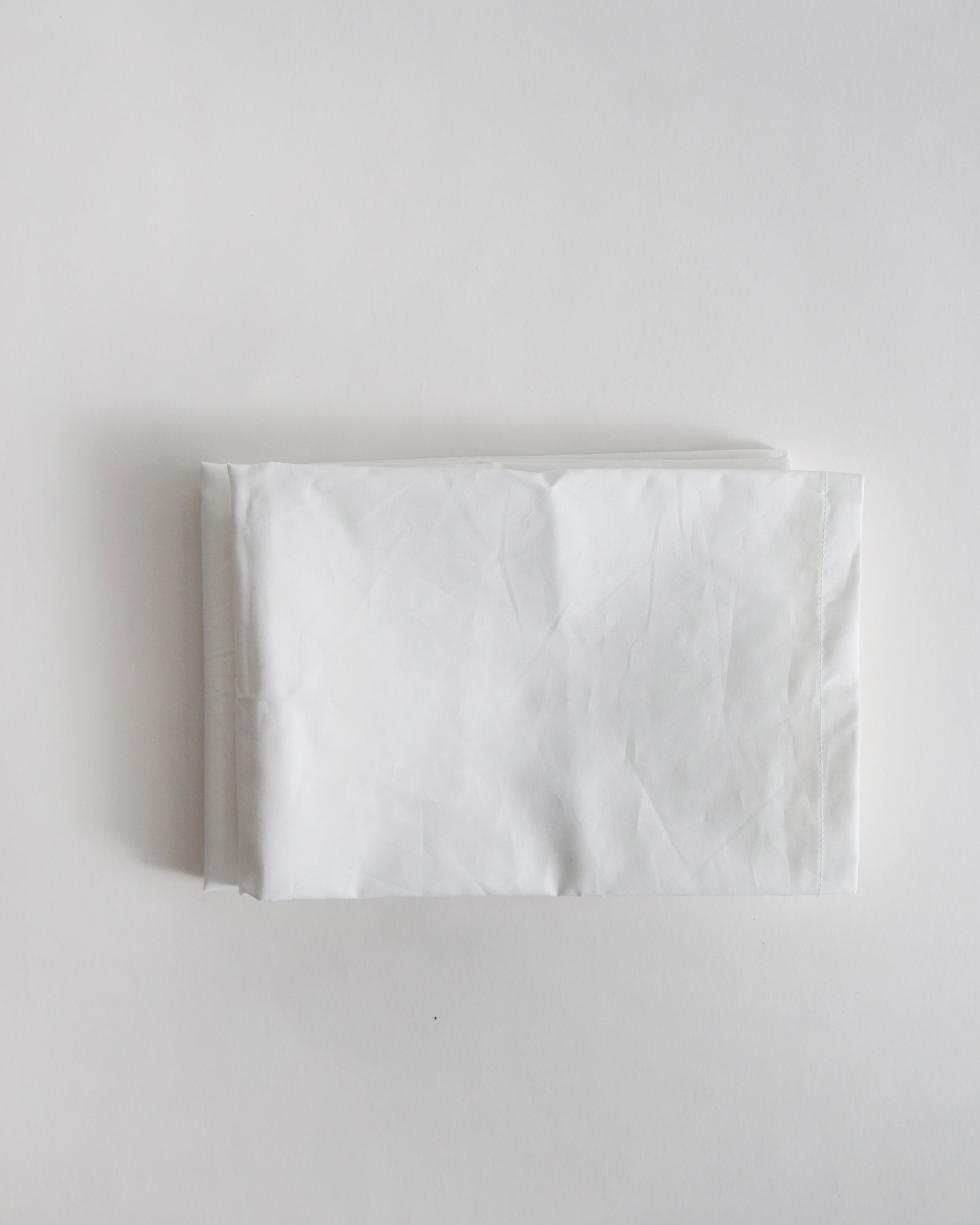 White folded pillowcase by iwata on a light gray background