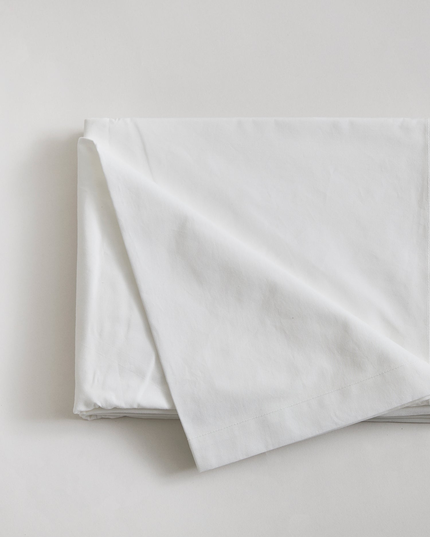 Folded white flat sheet by Iwata on a light gray background