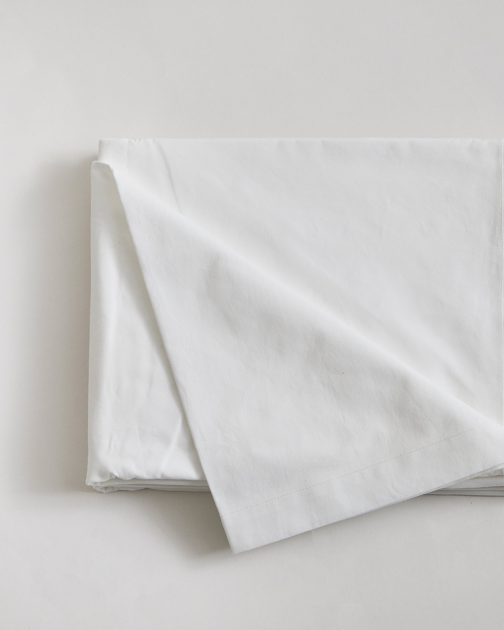 Folded white flat sheet by Iwata on a light gray background