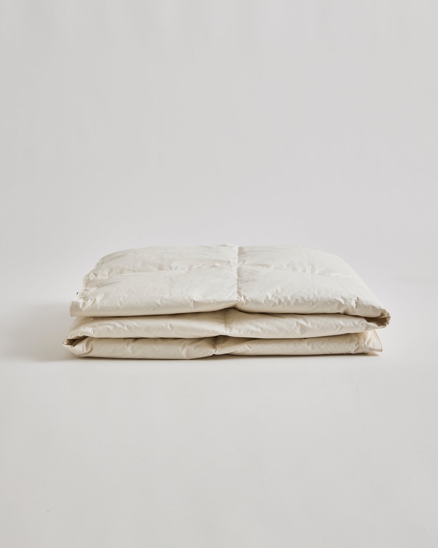 Folded Light Duvet by Iwata on a gray background