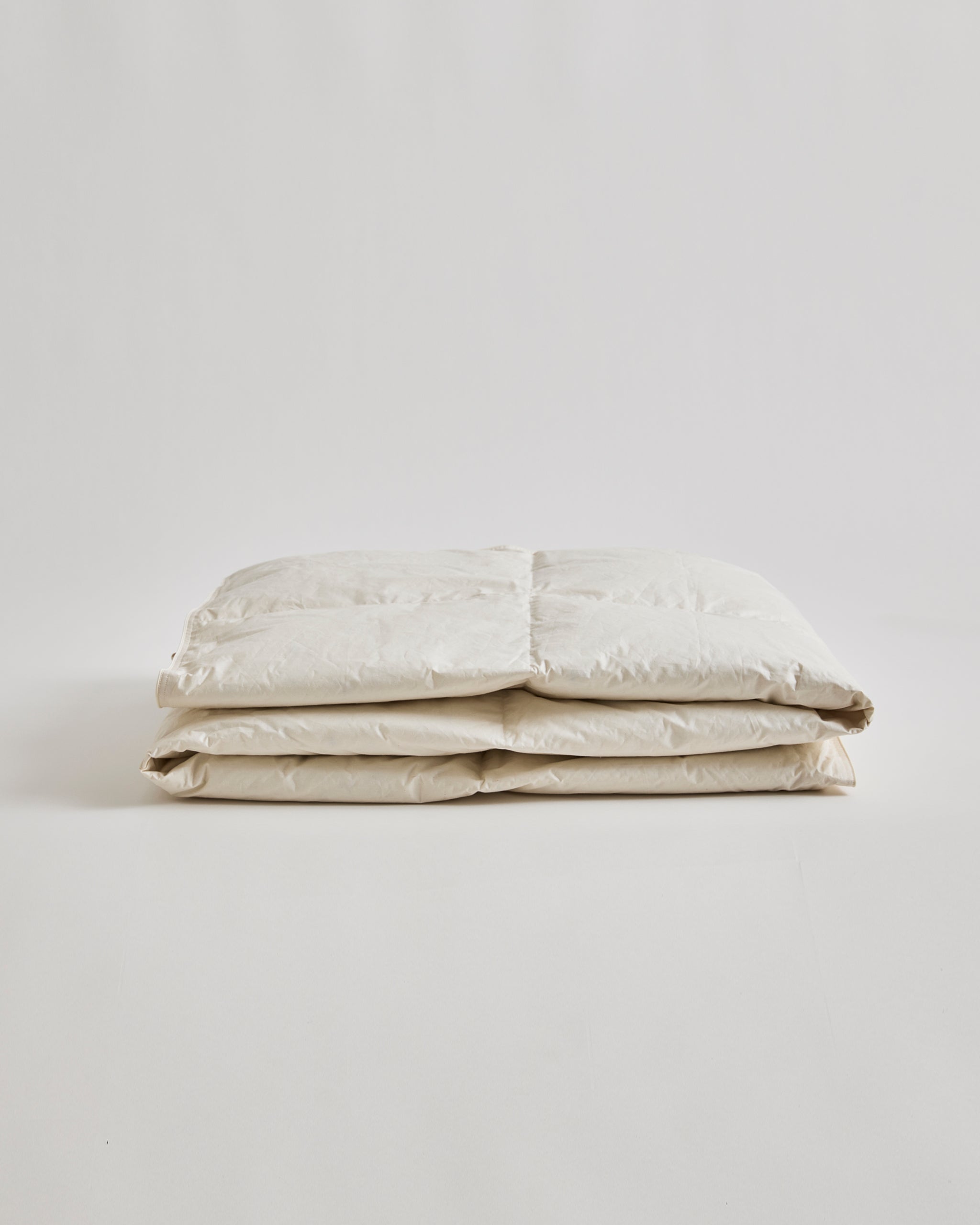 Folded Light Duvet by Iwata on a gray background