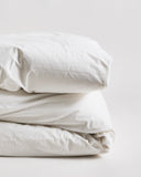 Up-close folded white duvet cover on a duvet by Iwata on a gray background