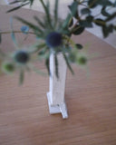 Close up in situation image of ceramic short white sculpture vase with foot with white overglaze by Masanobu Ando holding eucalyptus on oak table. 