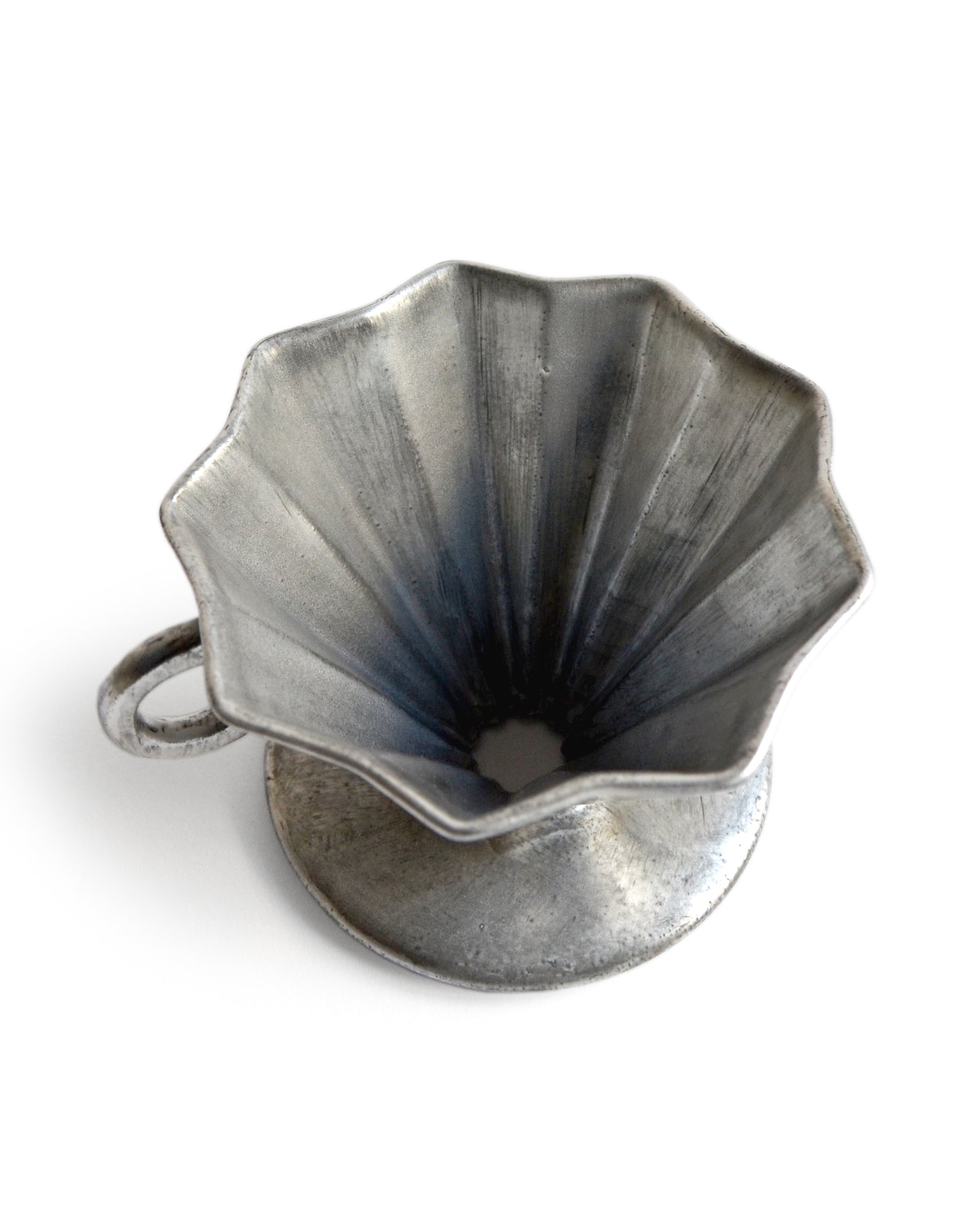Top view of the silver glazed coffee dripper silhouetted against white background.