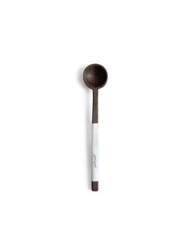Silhouetted image of hand carved tagaya wood spoon with label by Nalata Nalata against white background.