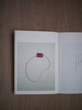 Top view of Crafts, and Then book by Ryuji Mitani open to a picture of a red art piece against light wood background. 