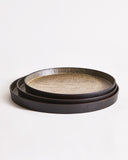 Stacked round trays with textured surface by Ryuji Mitani on a light gray background