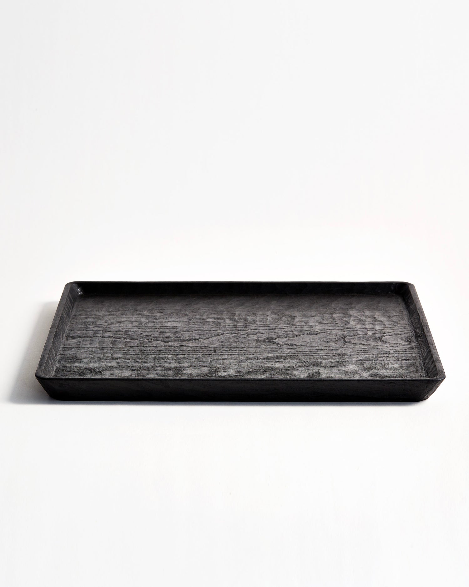 Front view of Carved Noir Wood Tray with Enju Wood by Ryuji Mitani against white-gray background.