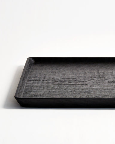 Cropped view of Carved Noir Wood Tray with Enju Wood by Ryuji Mitani against white-gray background. 