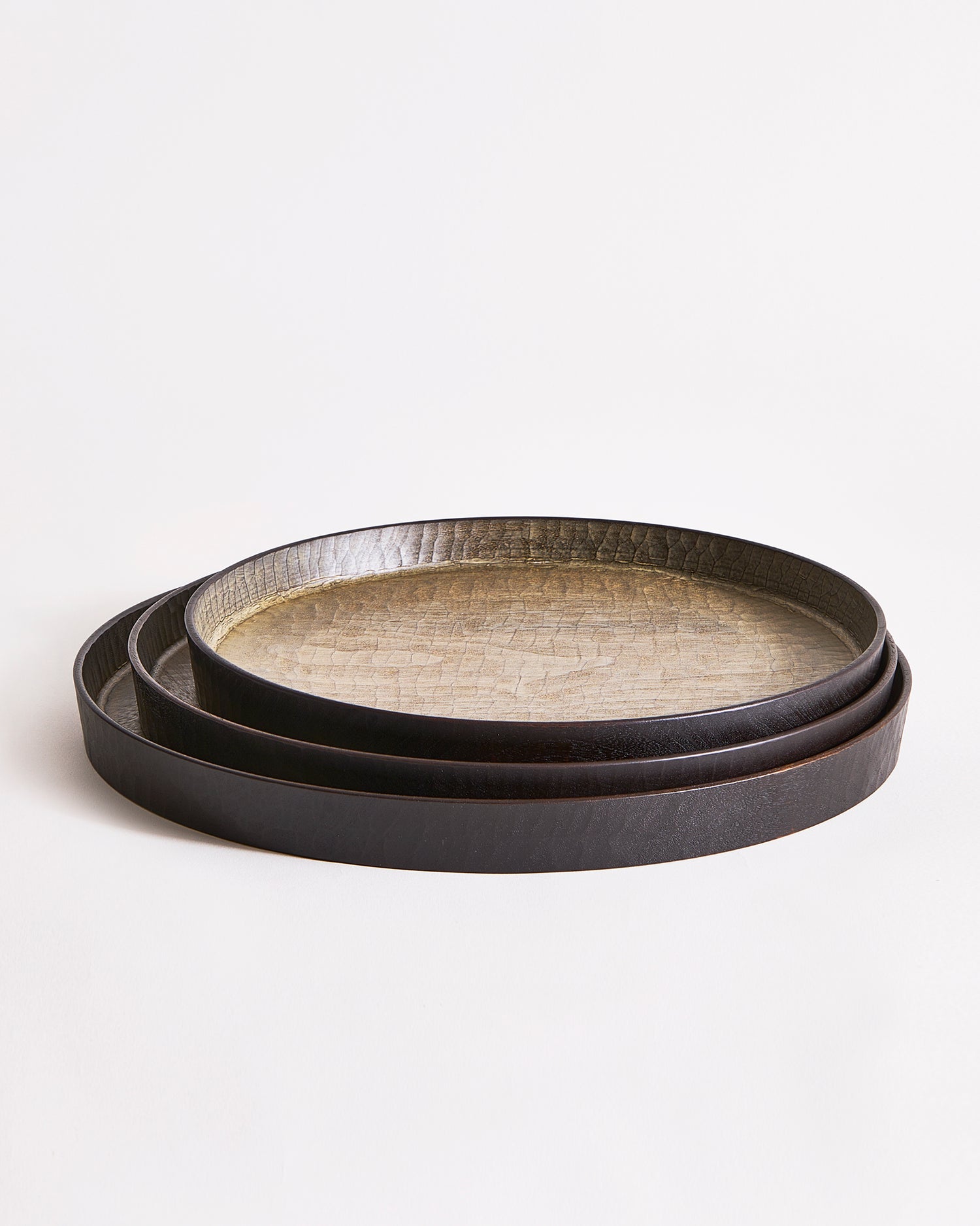 Stacked round wooden trays with textured surface by Ryuiji Mitani on a light gray background