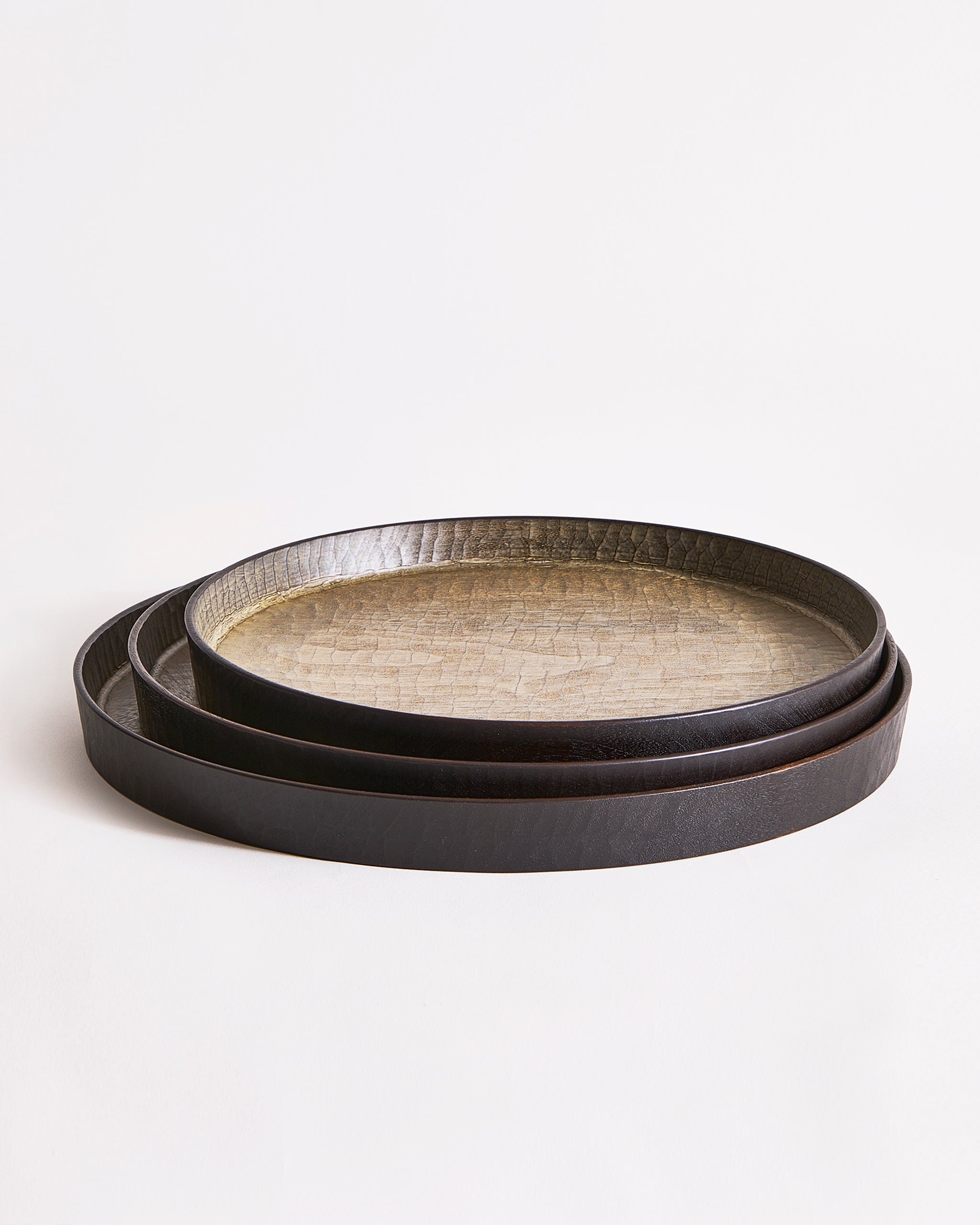 Stacked round wooden trays with textured surface by Ryuiji Mitani on a light gray background