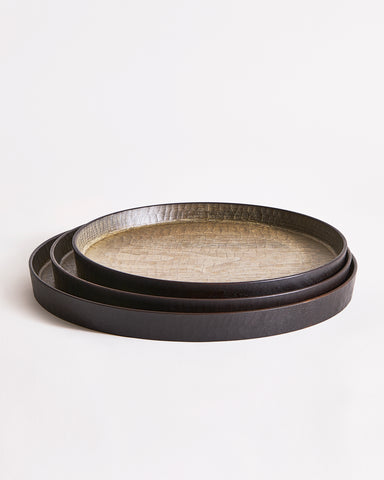 Stacked round wooden trays with textured surface by Ryuiji Mitani on a light gray background
