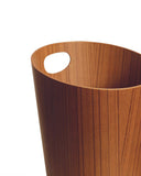 Cropped image focused on handle of teak paper waste basket with handle by Isamu Saito against white background.