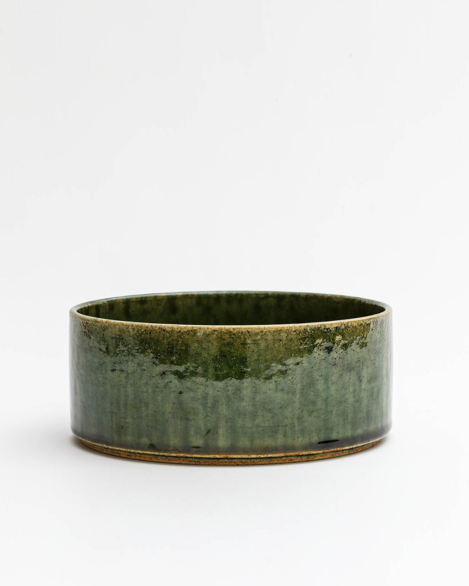 Silhouetted image of ceramic medium oribe bowl with deep green glaze by Time and Style against white-gray background.