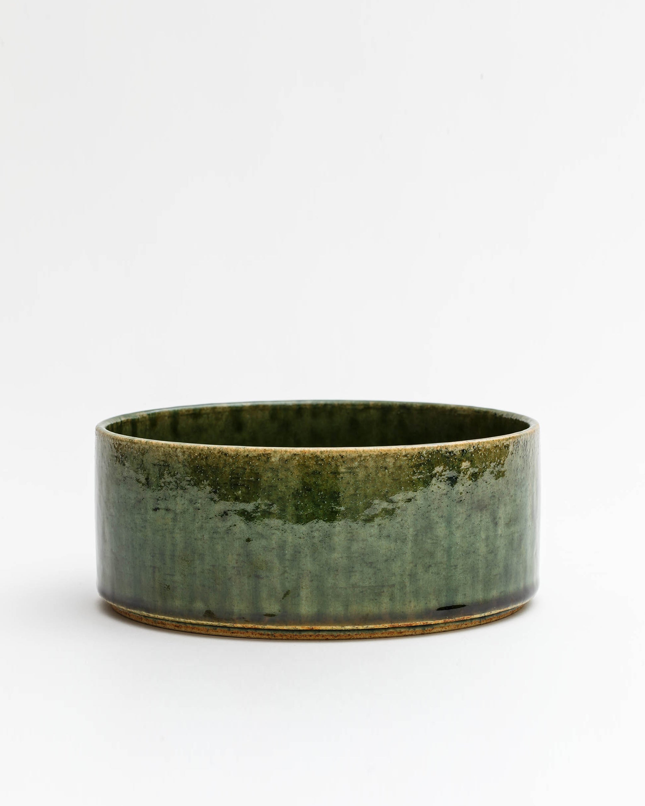 Silhouetted image of ceramic medium oribe bowl with deep green glaze by Time and Style against white-gray background.