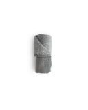 Face size zen charcoal towel rolled up silhouetted against white background.