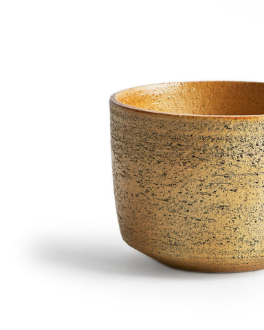 Detailed image of the silhouetted otosai yellow matcha bowl showing its textures on the exterior..